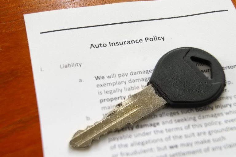 closeup of car key and auto insurance policy