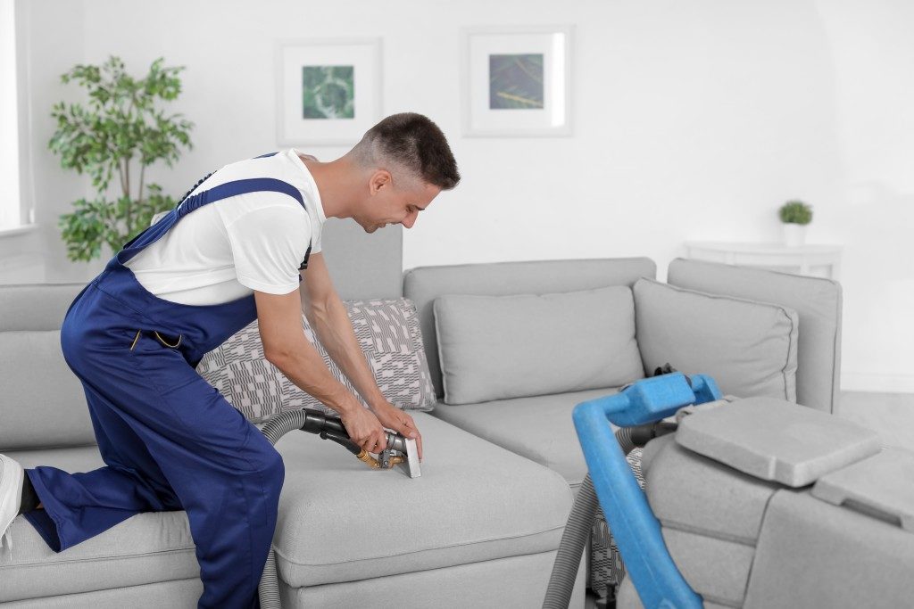 man vacuuming his couch
