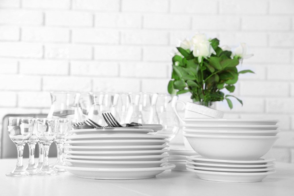 Clean plates, glasses and cutlery on white table