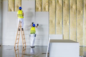 Two workers placing plaster on wall