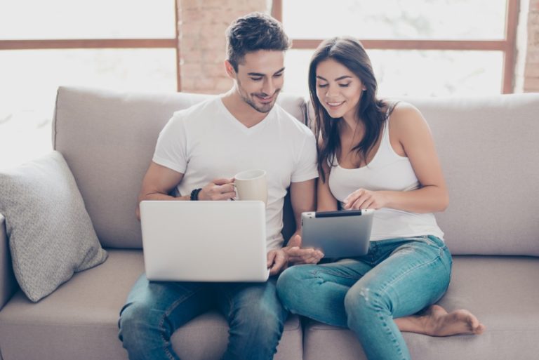 couple sitting on the couch checking info on devices