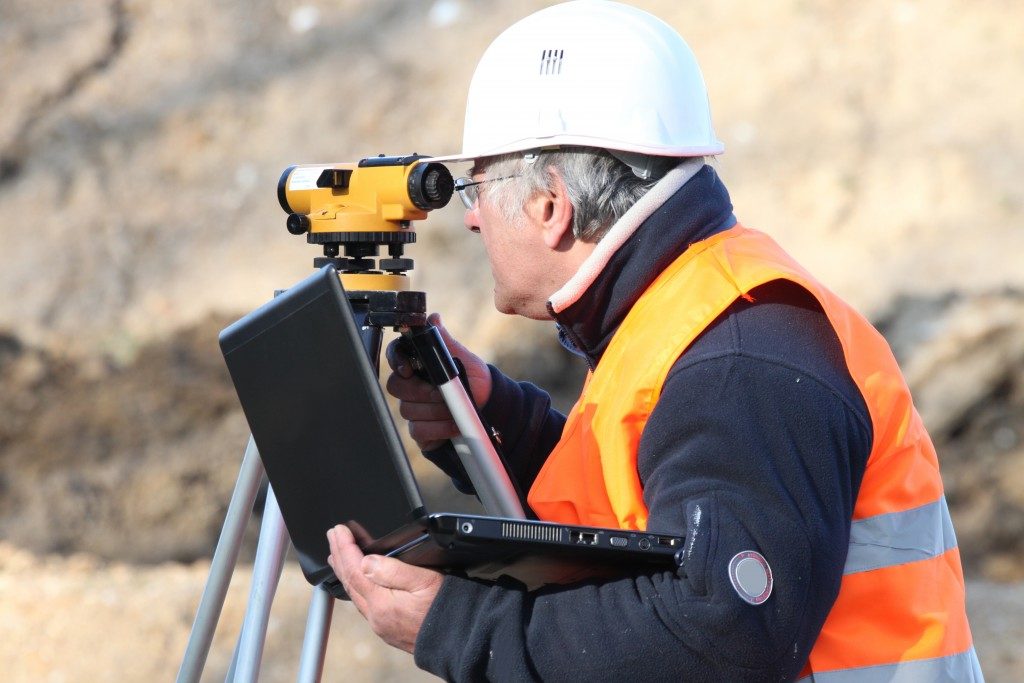 man holding a laptop while land surveying