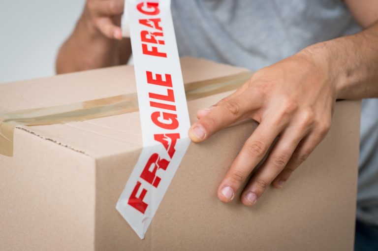 man placing fragile tape on the box