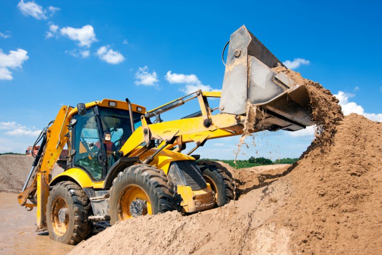yellow excavator holding a mound of soil to move it somewhere
