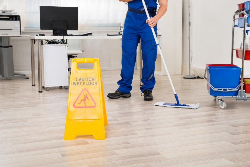 male janitor cleaning floor with mop in office