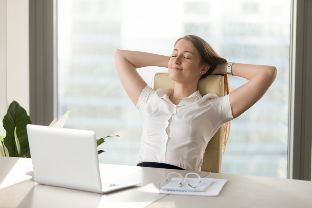 an employee relaxing at a workstation with hands above her head