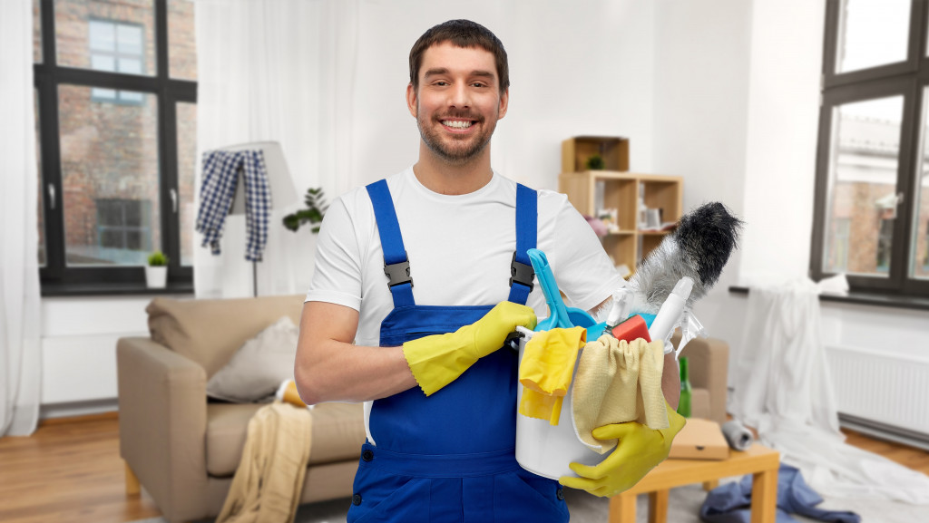 A male cleaner holding cleaning supplies
