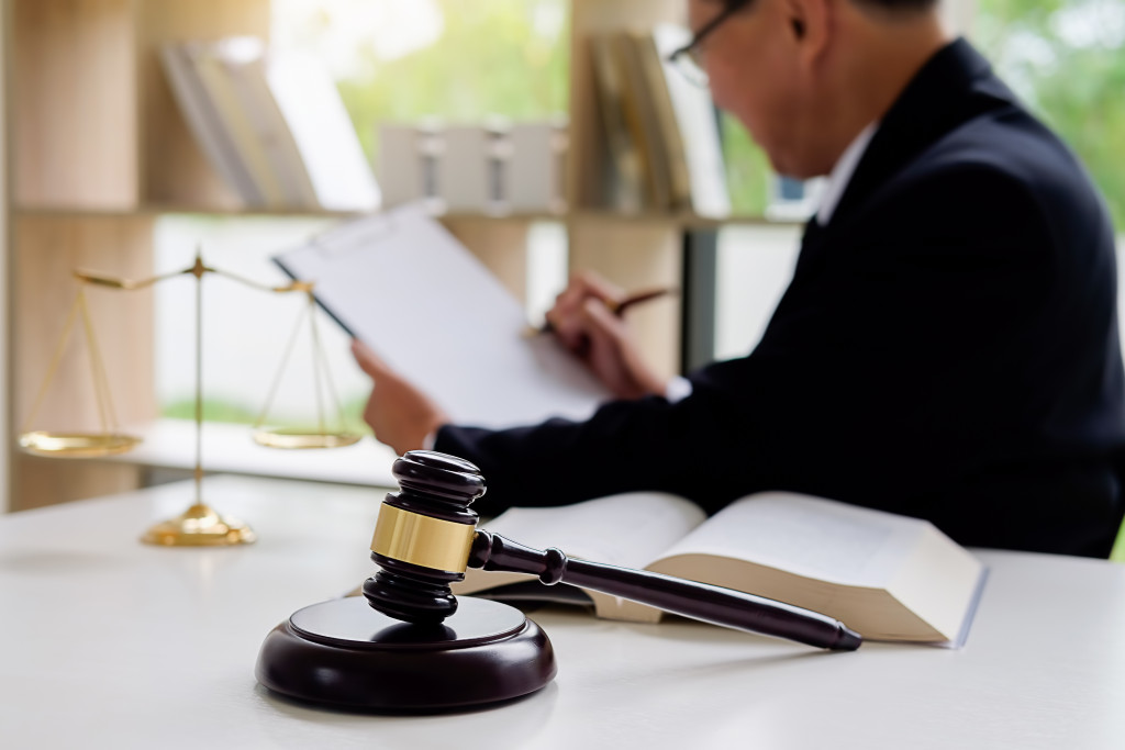 A lawyer sitting in front of a desk with scales, a book, and a gavel
