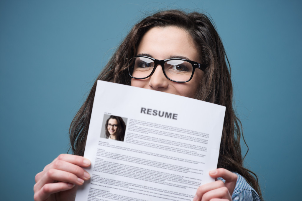 young woman hiding behid a paper resume