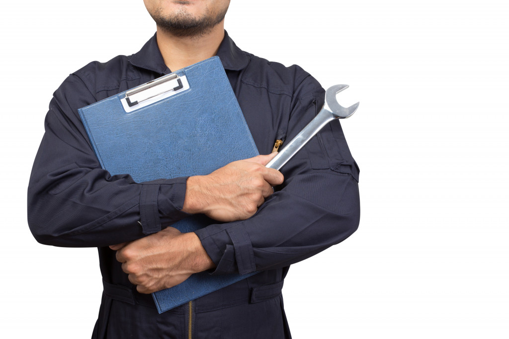 A worker holding documents and a wrench