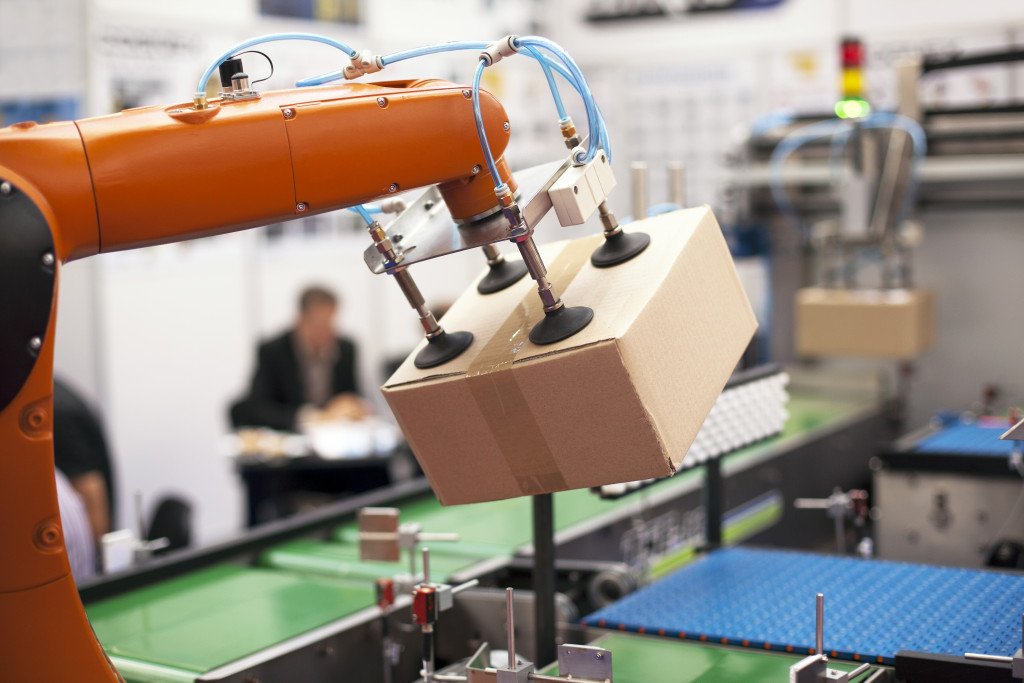 orange robotic arm lifting a box from conveyor belt for automated packaging