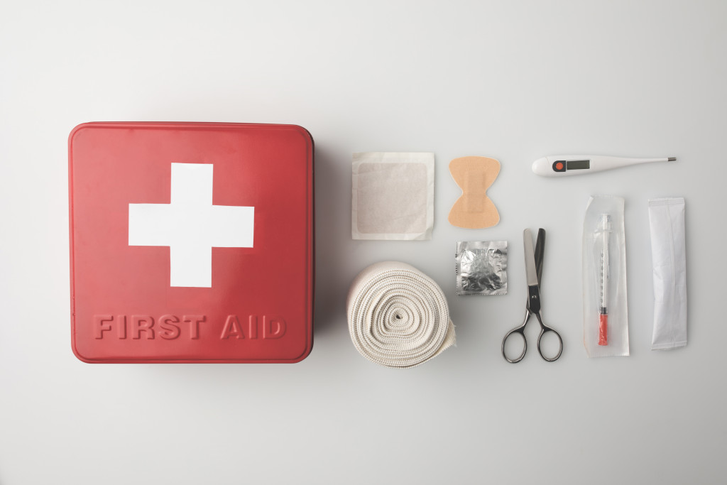 A red first aid kit with medical supplies beside it