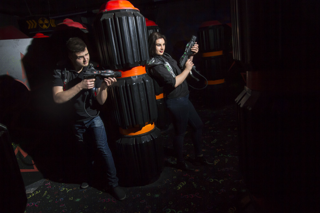 pair of office people playing with guns in an escape room area
