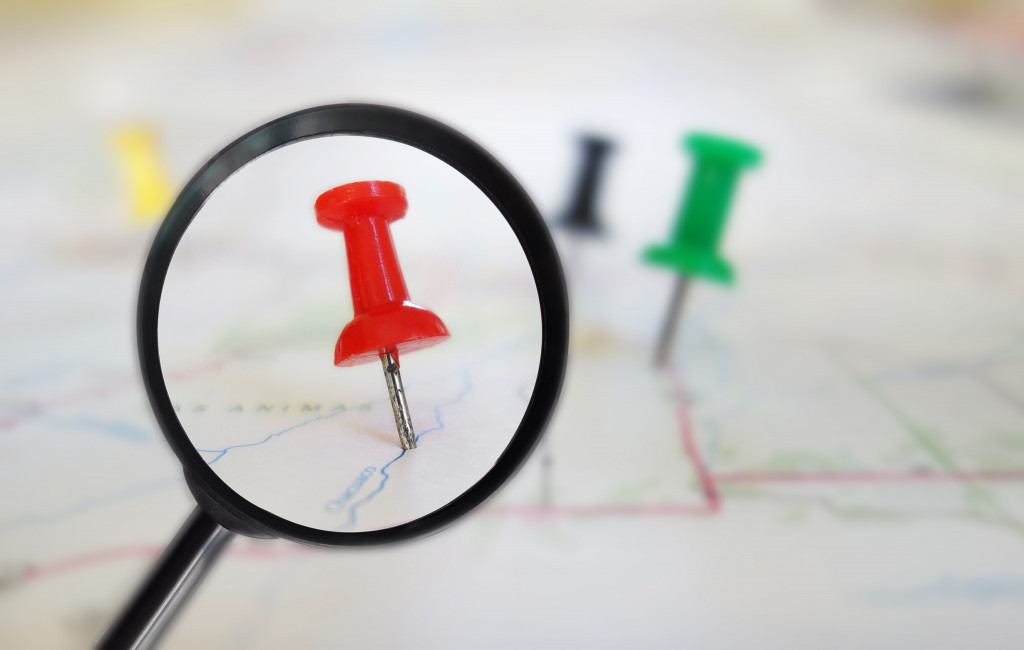 red pin under a magnifying glass in a map