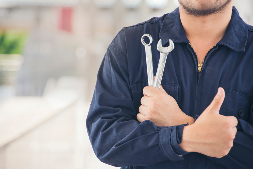 auto repair man doing thumbs up with tools in other hand